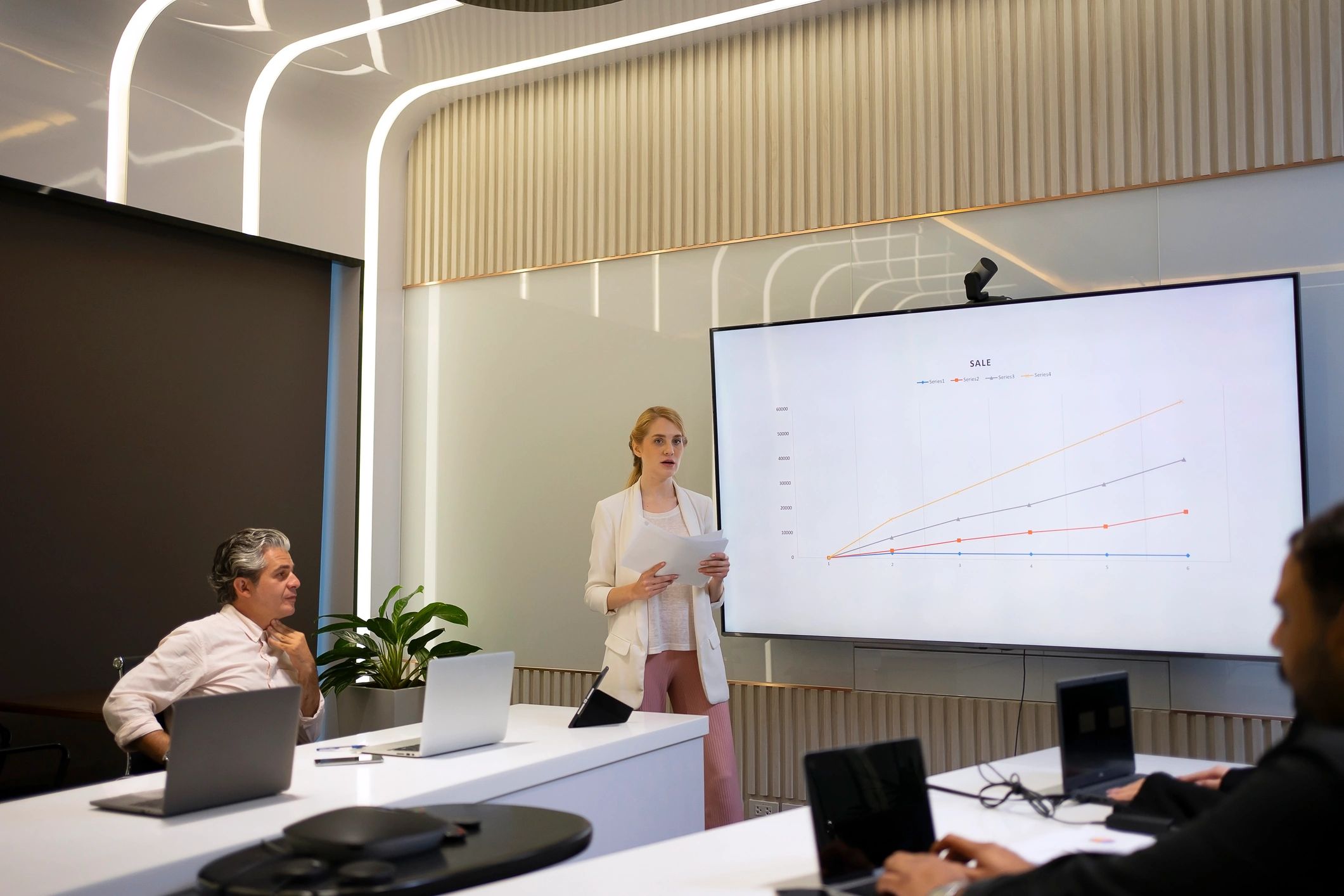 Equipo de trabajo en sala de reuniones con pantallas para presentación