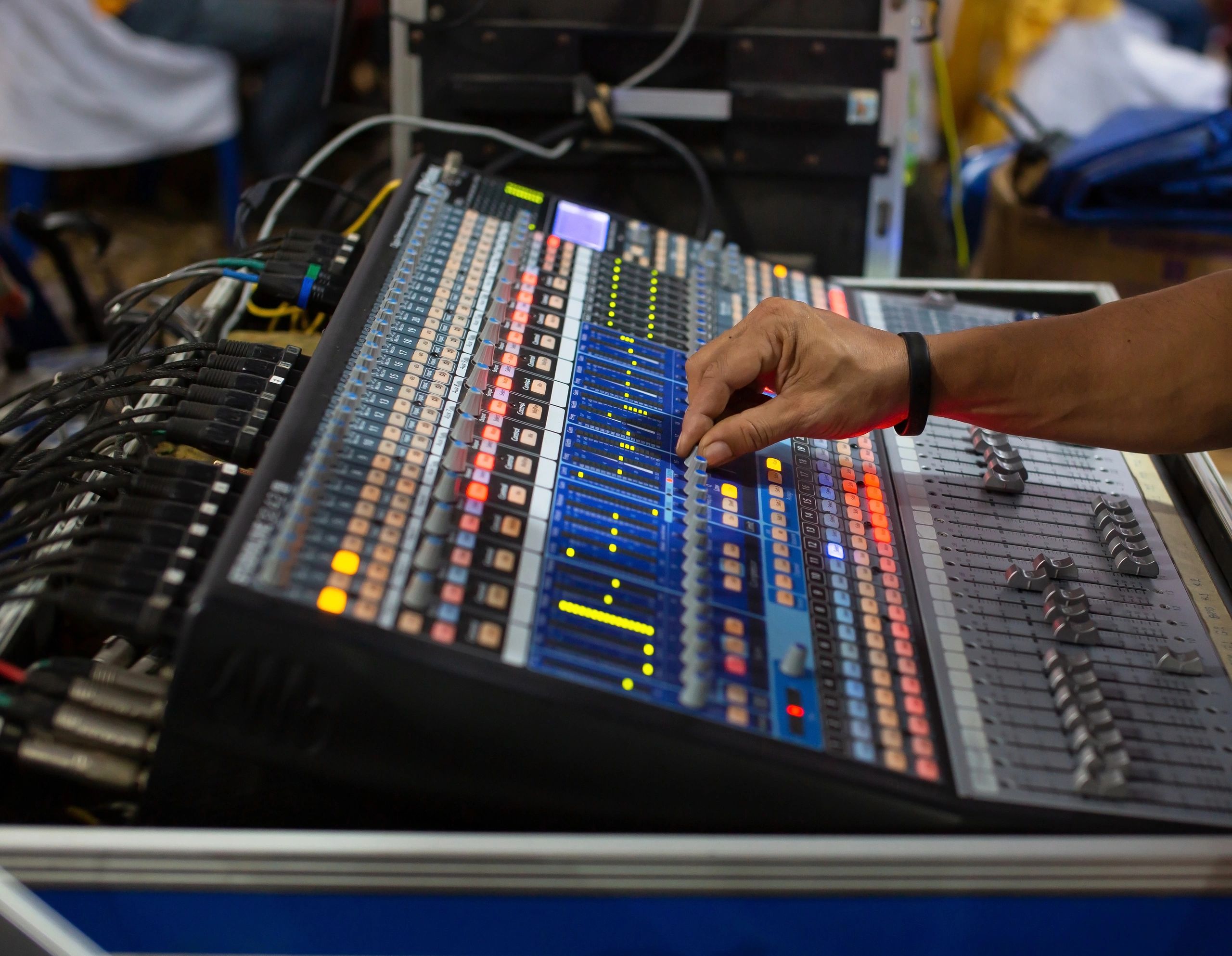 Manos operando una consola de sonido en vivo